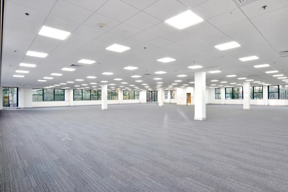 Large empty office building floor with white walls and grey carpeting